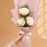 Three ivory roses bouquet with baby's breath in pink wrapping