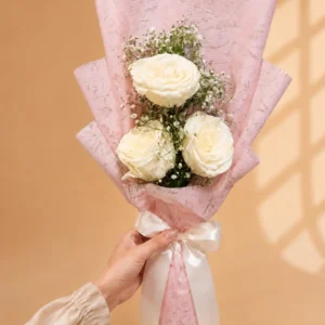 Three ivory roses bouquet with baby's breath in pink wrapping